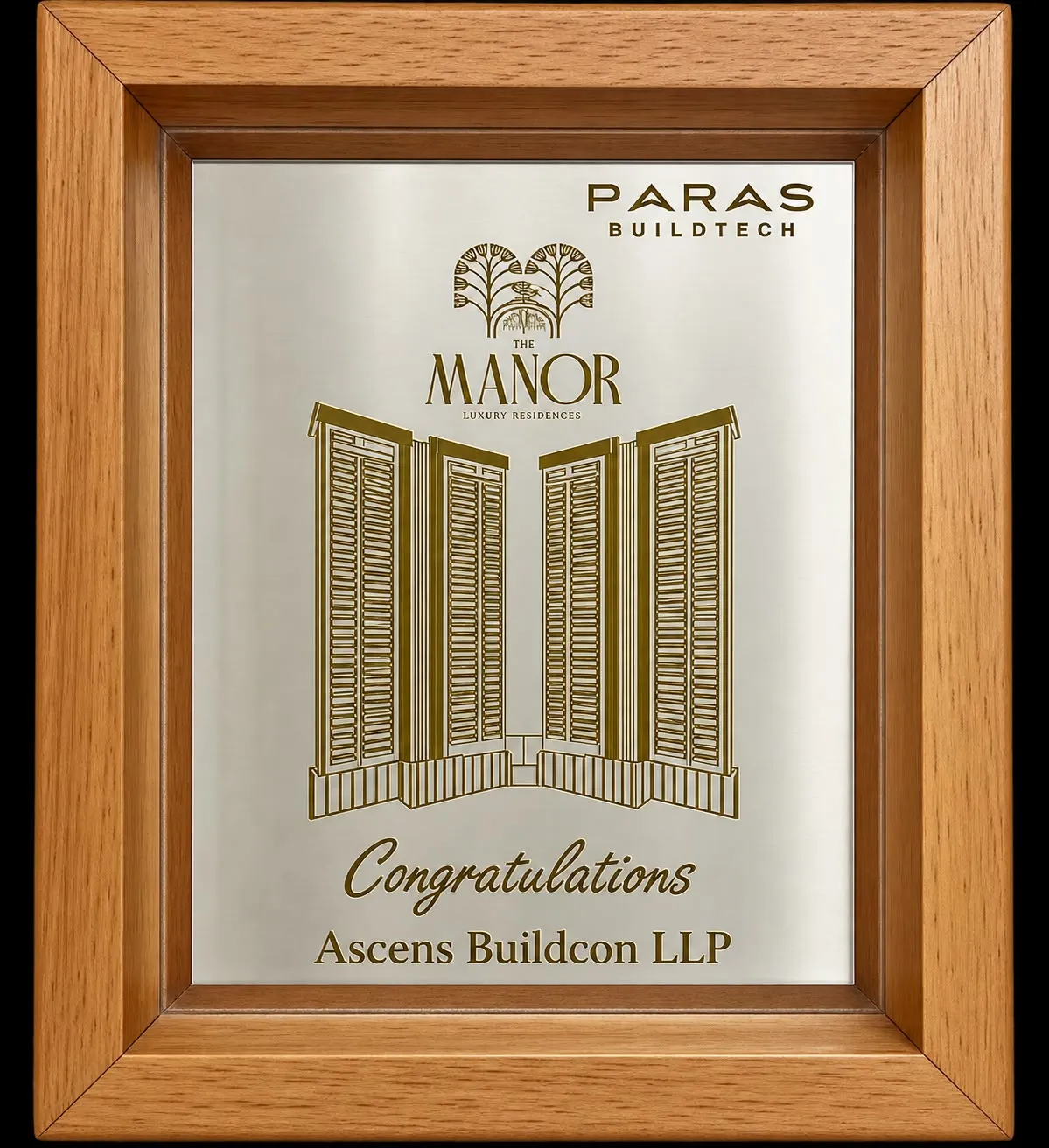 Wood-framed engraved plaque from Paras Buildtech congratulating Ascens Buildcon LLP on The Manor.